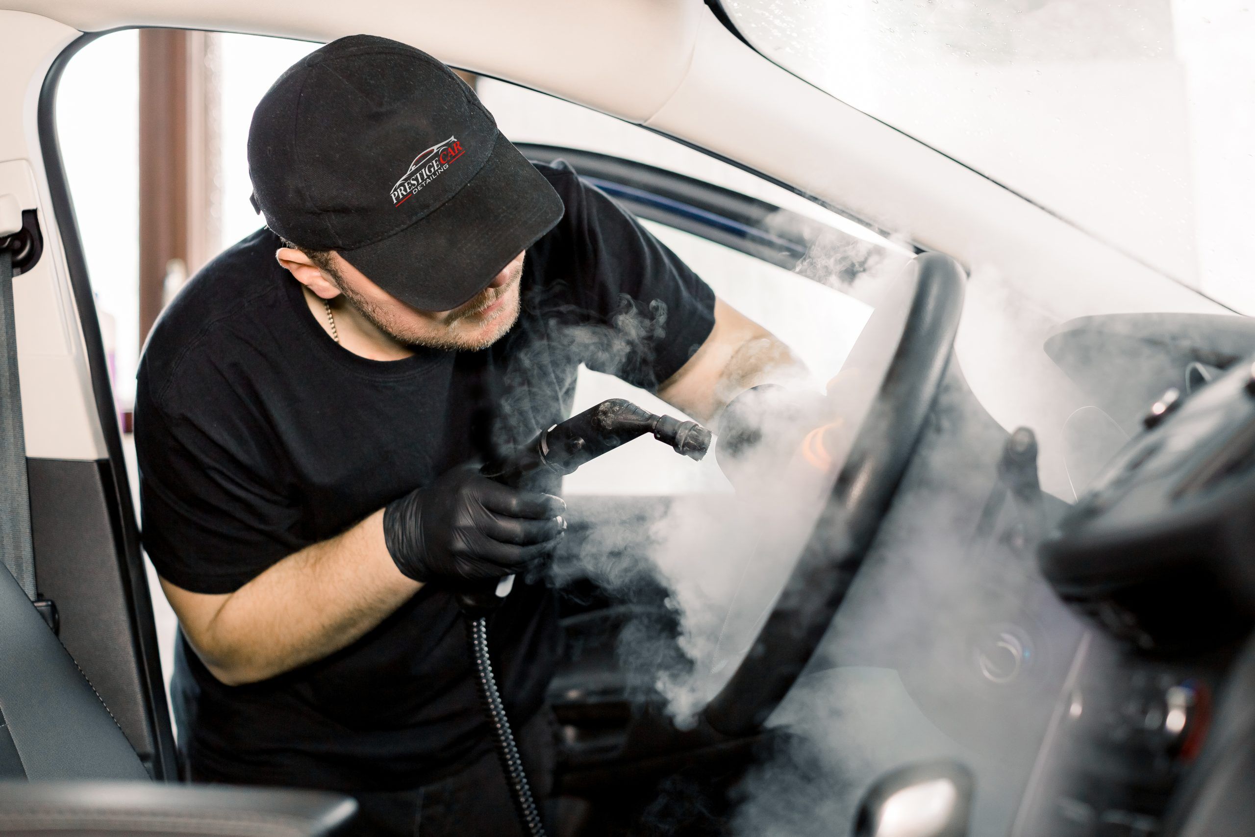 Car Detailing Steam Cleaning Concept Handsome Man In Black T Shirt And Cap Worker Of Car Wash Center Cleaning Car Interior With Hot Steam Cleaner Car Detailing Concept